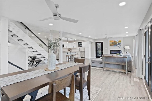 dining room with ceiling fan, light wood-type flooring, and sink