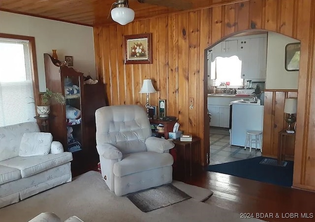 sitting room with sink, wooden ceiling, hardwood / wood-style floors, washer / dryer, and wooden walls