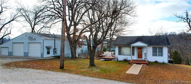 view of front of property featuring a front yard, a garage, an outdoor structure, and a wooden deck