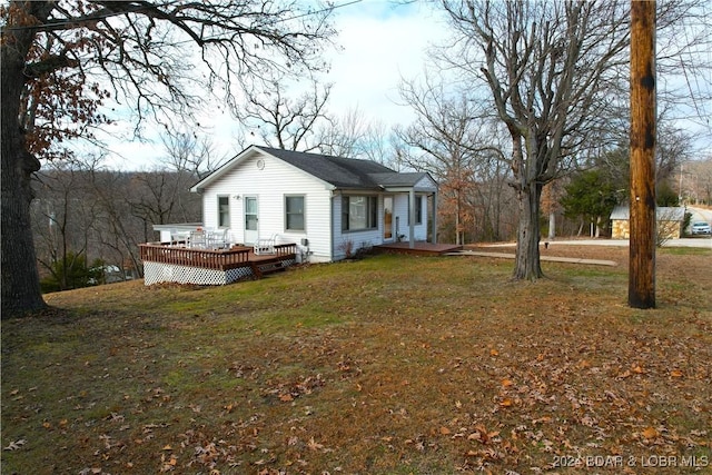 view of front of home with a deck and a front lawn