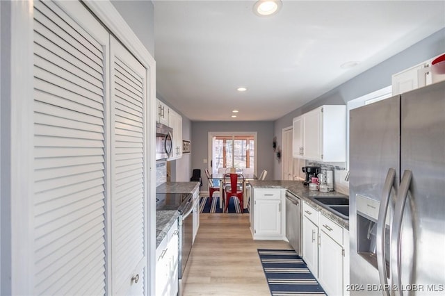 kitchen with backsplash, kitchen peninsula, white cabinetry, and appliances with stainless steel finishes