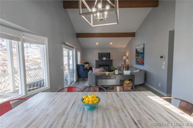 dining room with beamed ceiling, high vaulted ceiling, hardwood / wood-style flooring, and an inviting chandelier