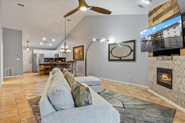 tiled living room featuring ceiling fan, a fireplace, and high vaulted ceiling