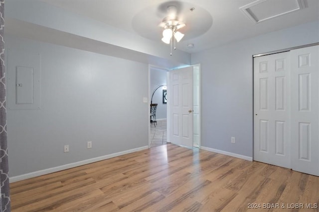 unfurnished bedroom featuring electric panel, ceiling fan, a closet, and light hardwood / wood-style floors