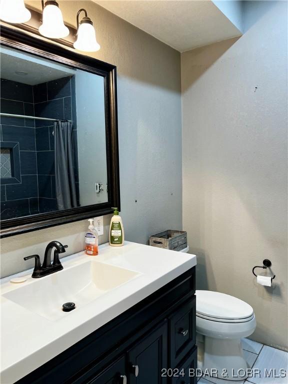 bathroom featuring a shower with shower curtain, tile patterned floors, vanity, and toilet