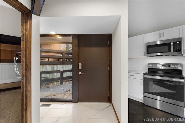 kitchen featuring white cabinetry, backsplash, and appliances with stainless steel finishes