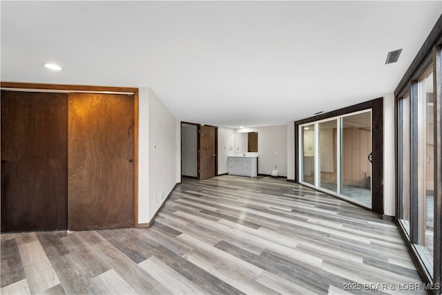 unfurnished living room with light hardwood / wood-style floors and a wall of windows