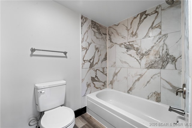 bathroom with hardwood / wood-style flooring, toilet, and tiled shower / bath