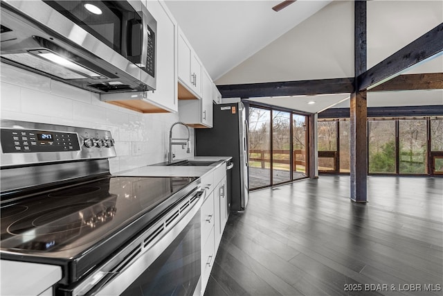 kitchen featuring white cabinetry, sink, dark wood-type flooring, vaulted ceiling with beams, and appliances with stainless steel finishes