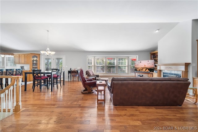 living room with a healthy amount of sunlight, wood-type flooring, a fireplace, and an inviting chandelier