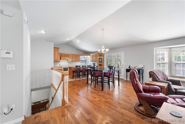 dining area featuring a chandelier, vaulted ceiling, and light hardwood / wood-style flooring