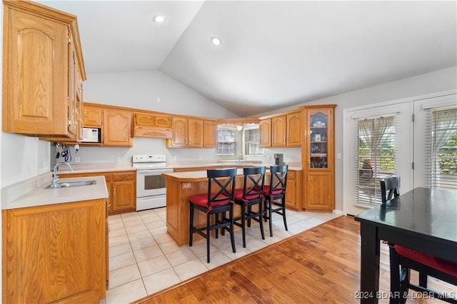 kitchen featuring a breakfast bar, white appliances, sink, a kitchen island, and light tile patterned flooring