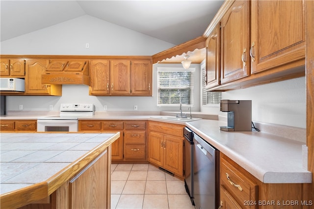 kitchen with sink, premium range hood, lofted ceiling, white appliances, and light tile patterned flooring