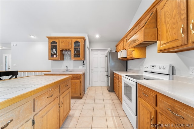 kitchen with tile countertops, white appliances, sink, and light tile patterned floors