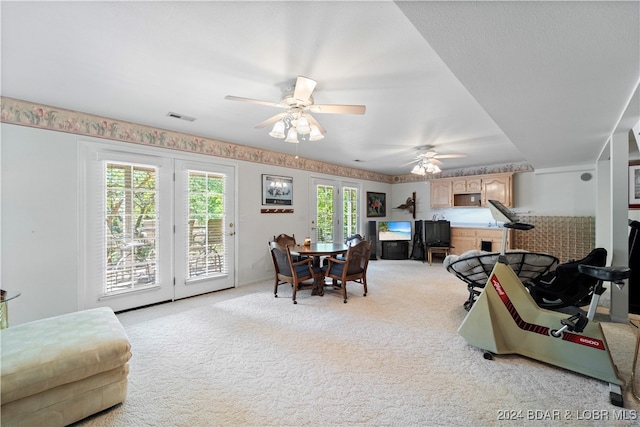 carpeted dining space with french doors, ceiling fan, and a healthy amount of sunlight