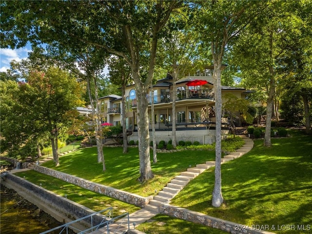 rear view of house with a lawn, a balcony, and a water view