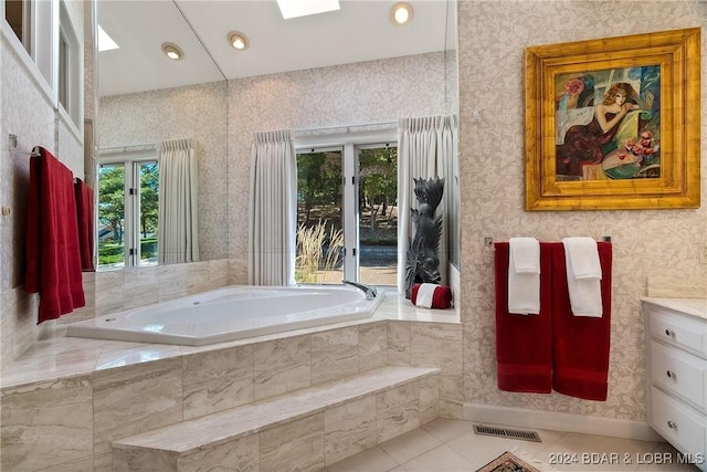 bathroom with tiled bath, a wealth of natural light, tile patterned flooring, and vanity