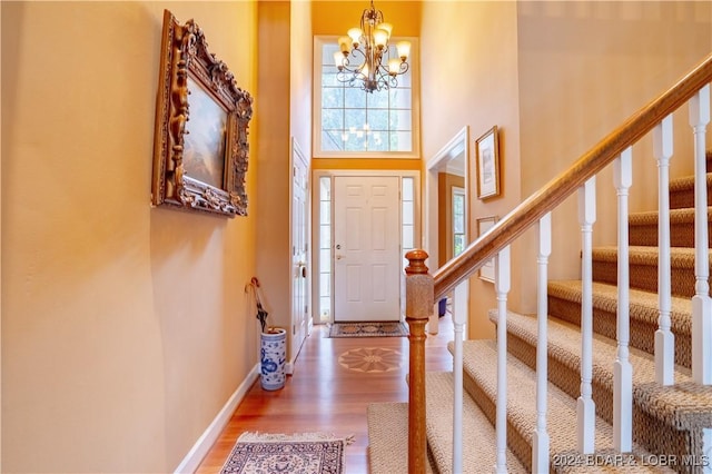 foyer featuring hardwood / wood-style flooring, a high ceiling, and an inviting chandelier