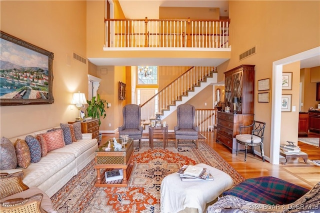 living room featuring a notable chandelier, light wood-type flooring, and a high ceiling