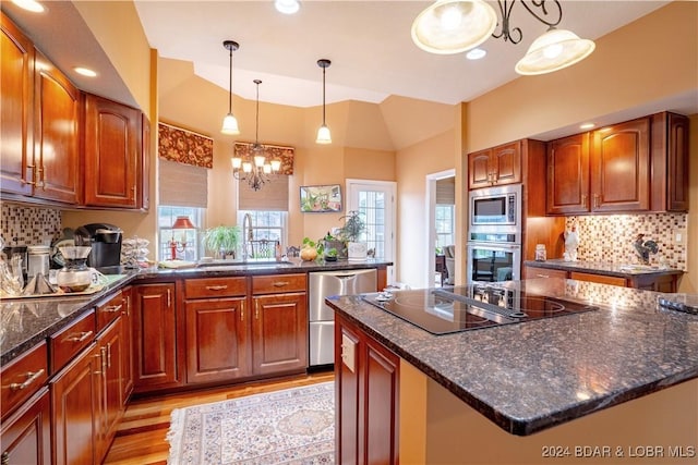 kitchen featuring stainless steel appliances, sink, an inviting chandelier, a center island, and plenty of natural light