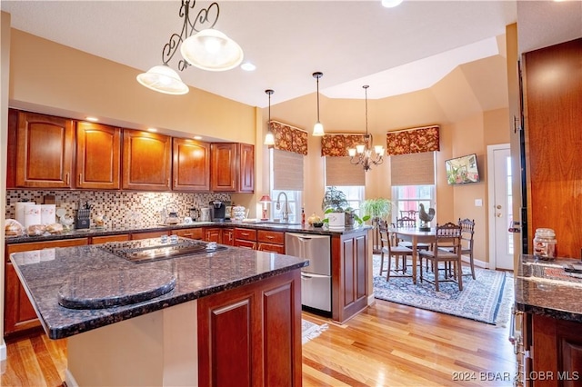 kitchen with appliances with stainless steel finishes, backsplash, dark stone countertops, a center island, and hanging light fixtures