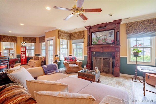 living room featuring ceiling fan, a large fireplace, and ornamental molding