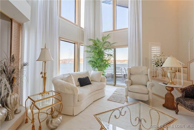 living area with a water view and a high ceiling