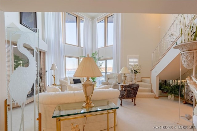 living area with stairs, a high ceiling, and carpet flooring