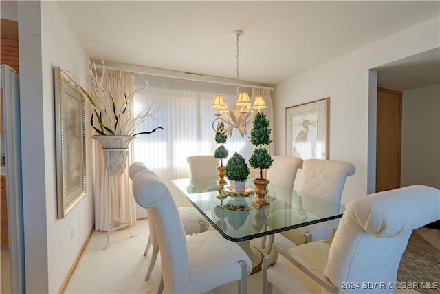 dining area featuring a chandelier, light carpet, and baseboards