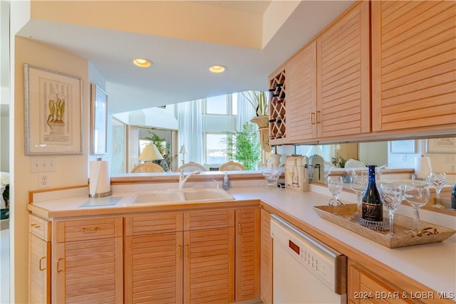 kitchen with light brown cabinetry, dishwasher, and sink