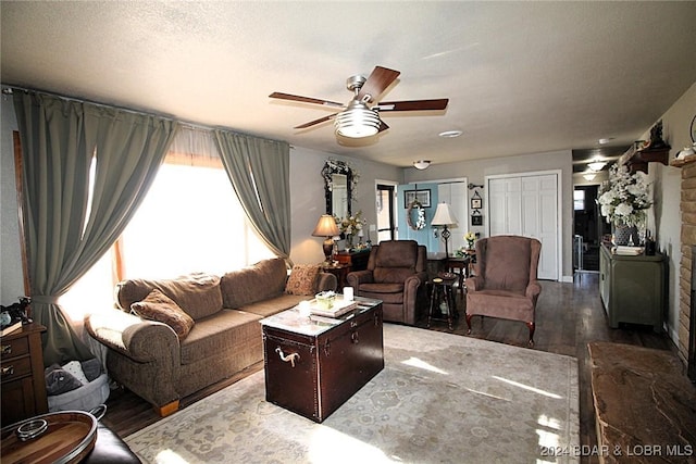 living room featuring a stone fireplace, ceiling fan, and wood-type flooring