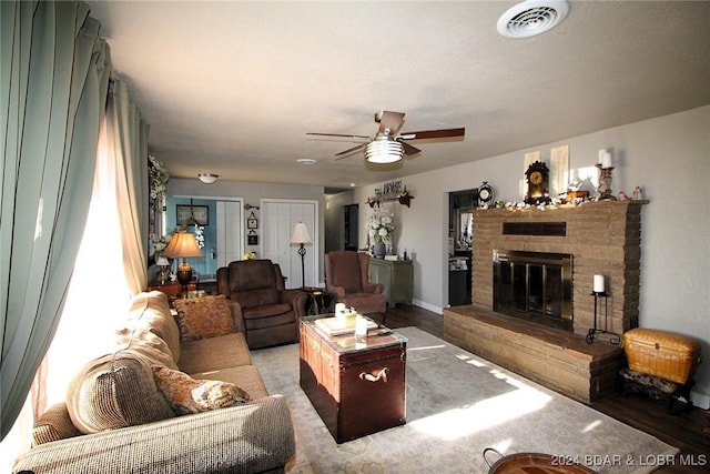 living room with ceiling fan and a fireplace