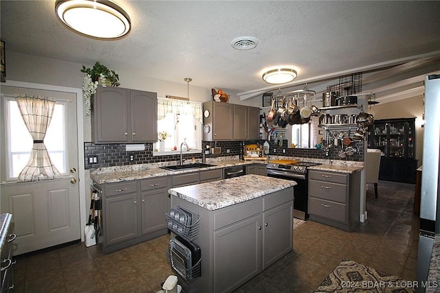 kitchen with electric stove, sink, hanging light fixtures, gray cabinets, and a kitchen island