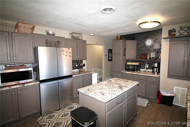 kitchen featuring gray cabinetry, a center island, appliances with stainless steel finishes, and tasteful backsplash