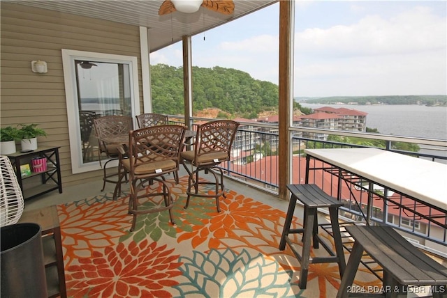 sunroom / solarium featuring ceiling fan, plenty of natural light, and a water view