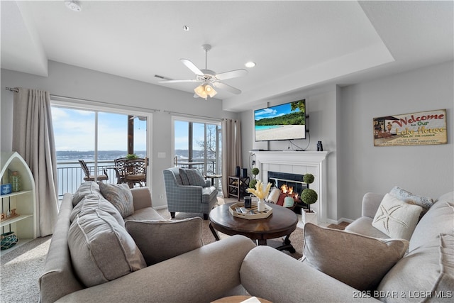 living room with a tile fireplace and ceiling fan