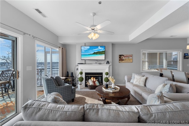 living room with a tile fireplace and ceiling fan