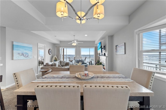 dining space with carpet flooring and ceiling fan with notable chandelier