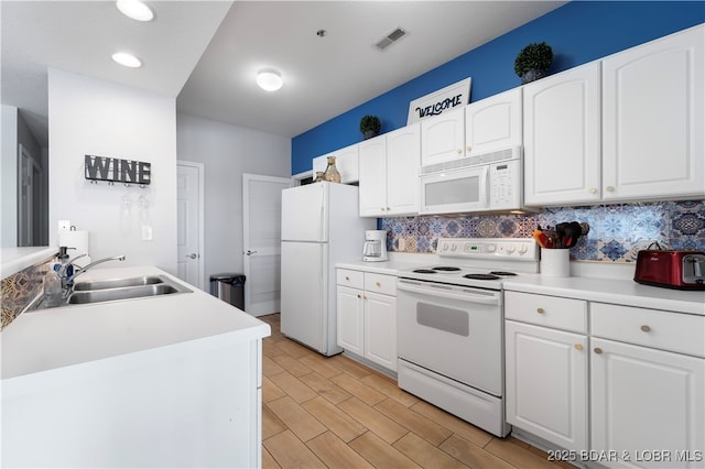 kitchen featuring white appliances, tasteful backsplash, and white cabinetry