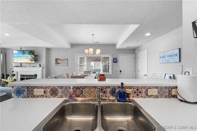 kitchen with a tile fireplace, sink, a chandelier, pendant lighting, and a textured ceiling