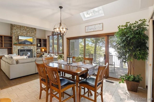 dining space with a fireplace, light tile patterned floors, a skylight, and a chandelier