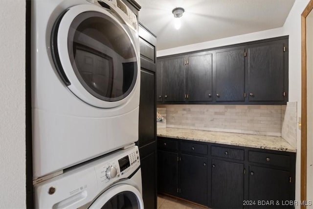 clothes washing area with stacked washer / dryer and cabinets