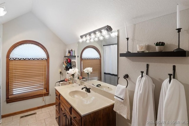 bathroom with tile patterned flooring, vanity, and lofted ceiling