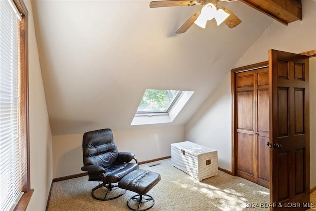 living area with ceiling fan, light colored carpet, and lofted ceiling with skylight