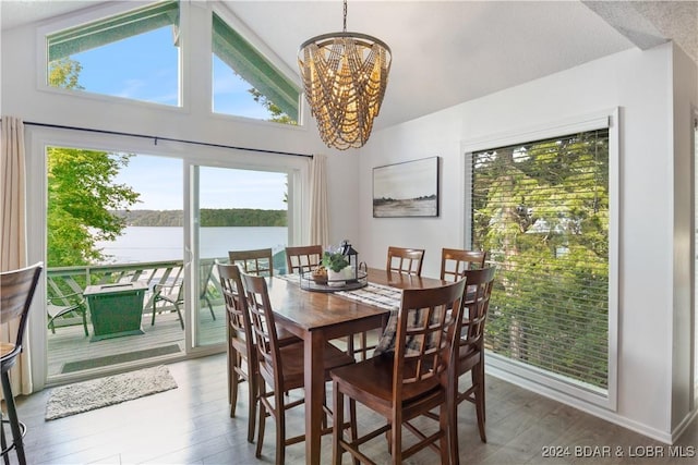 dining area featuring a notable chandelier, dark hardwood / wood-style floors, a water view, and high vaulted ceiling