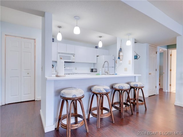 kitchen with white cabinets, a kitchen bar, kitchen peninsula, and hanging light fixtures