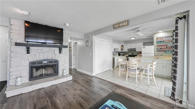 living room with ceiling fan, a fireplace, and light wood-type flooring