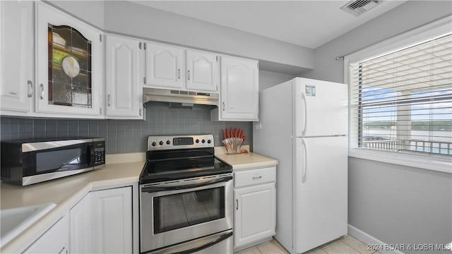 kitchen with sink, light tile patterned floors, appliances with stainless steel finishes, white cabinetry, and decorative backsplash