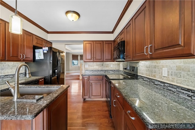 kitchen with sink, dark hardwood / wood-style flooring, dark stone counters, pendant lighting, and black appliances