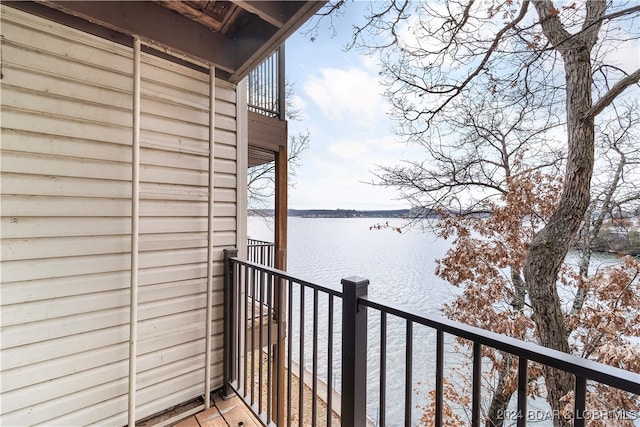 snow covered back of property featuring a water view